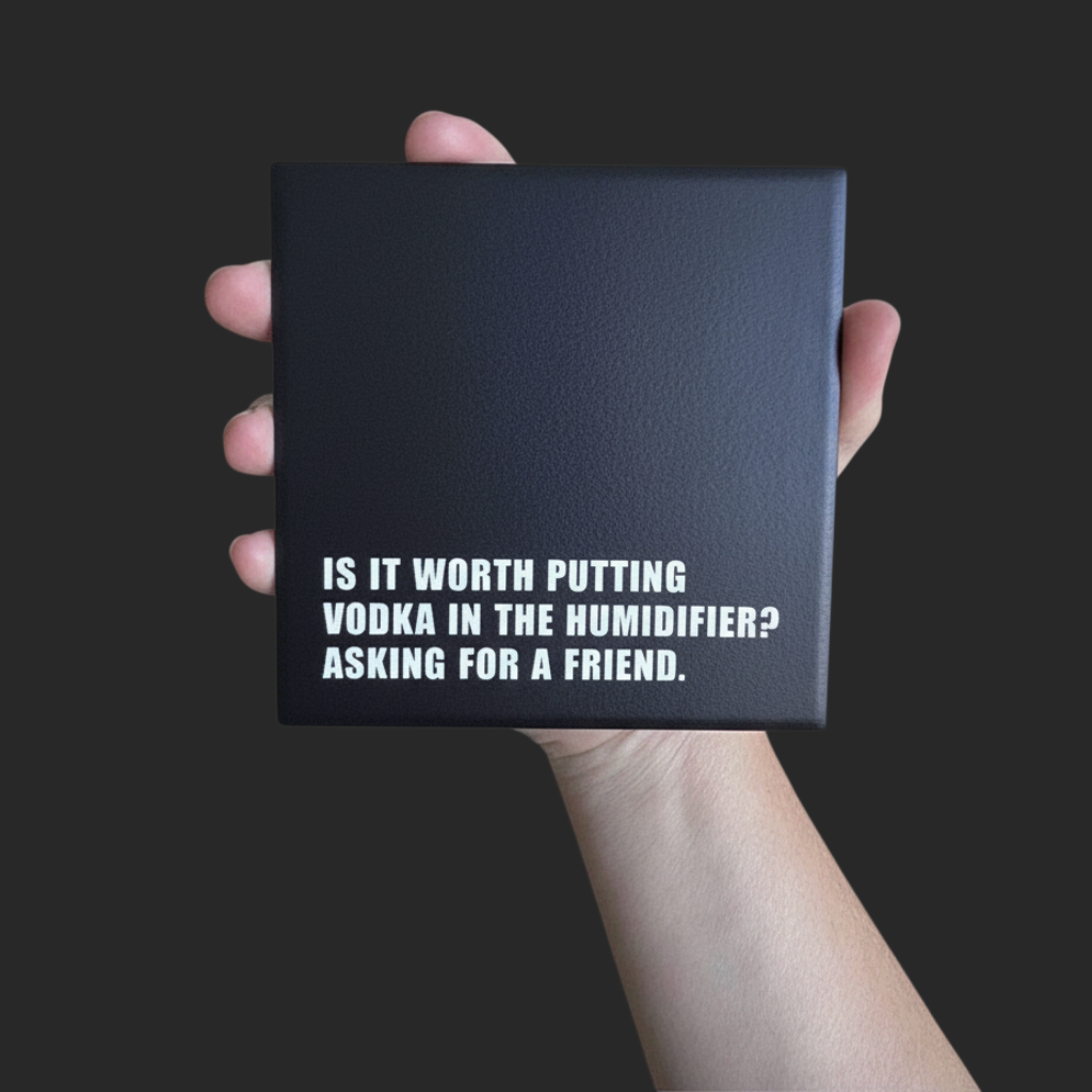 Let's Be Frank Australia square black ceramic coaster with white text reading Is it worth putting vodka in the humidifier