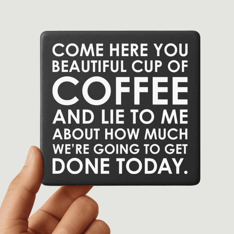 Coaster with humorous coffee quote held by a hand against a light gray background